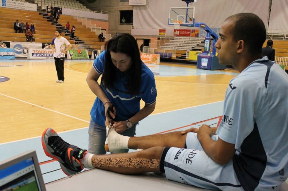 Belén Díaz vendando el tobillo de un jugador a pie de pista durante un partido del Breogán